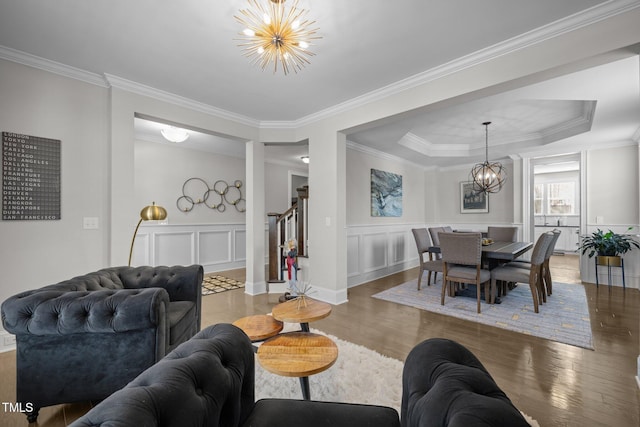 living room with a notable chandelier, crown molding, dark hardwood / wood-style floors, and a raised ceiling