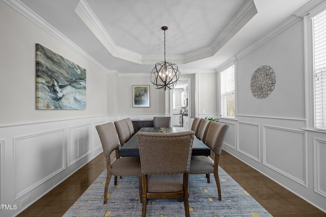 dining area with crown molding, dark hardwood / wood-style floors, an inviting chandelier, and a tray ceiling