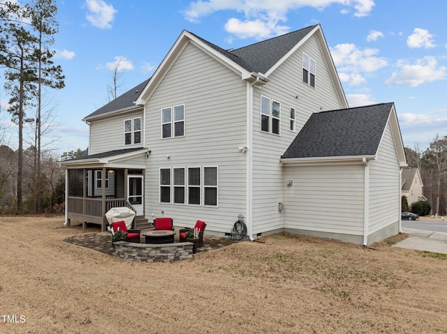 rear view of house with an outdoor fire pit, a patio, and a lawn