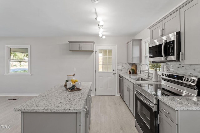 kitchen with appliances with stainless steel finishes, gray cabinets, sink, and backsplash