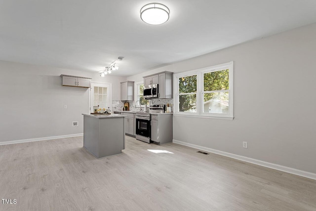 kitchen featuring tasteful backsplash, appliances with stainless steel finishes, a center island, and gray cabinetry