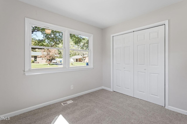 unfurnished bedroom with light colored carpet and a closet