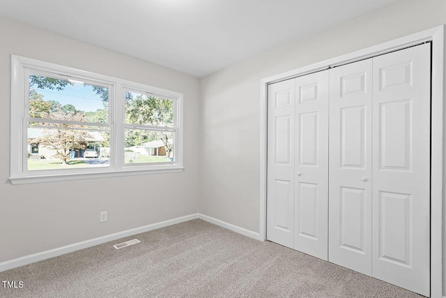 unfurnished bedroom with light carpet and a closet