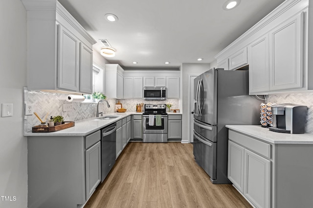 8005 Chatahoochie Ln, Raleigh, NC 27616 - kitchen featuring appliances with stainless steel finishes, decorative backsplash, light wood-style floors, gray cabinetry, and light countertops