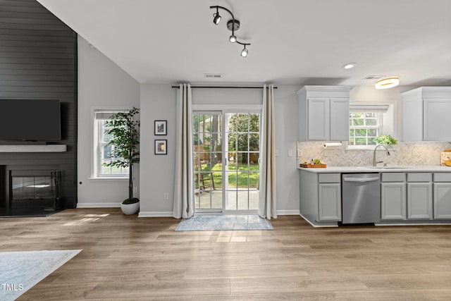 8005 Chatahoochie Ln, Raleigh, NC 27616 - kitchen featuring dishwasher, a fireplace, light countertops, decorative backsplash, and light wood finished floors