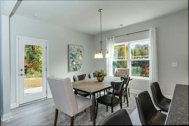 dining space featuring a healthy amount of sunlight, a notable chandelier, and light hardwood / wood-style flooring