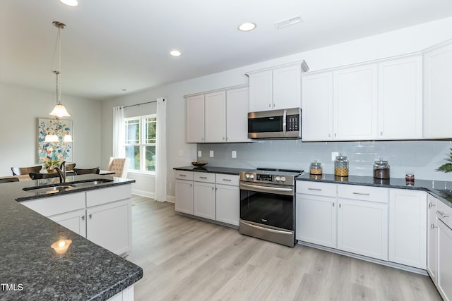 kitchen featuring white cabinetry, stainless steel appliances, sink, and hanging light fixtures