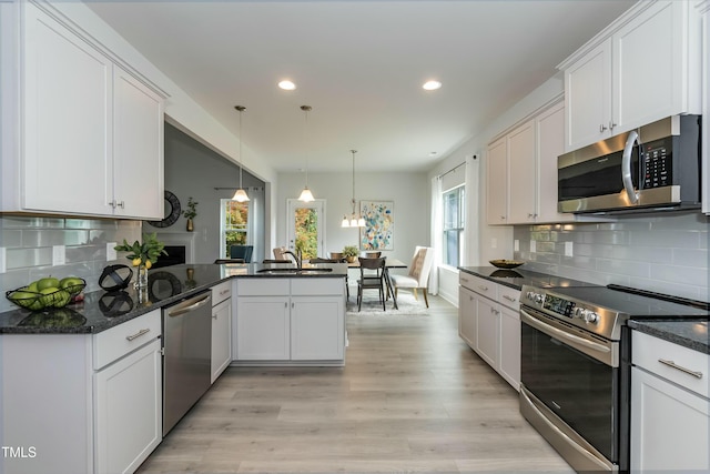 kitchen with white cabinetry, appliances with stainless steel finishes, kitchen peninsula, pendant lighting, and decorative backsplash