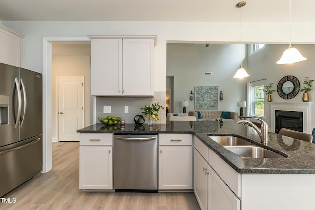 kitchen with sink, white cabinets, decorative backsplash, hanging light fixtures, and stainless steel appliances