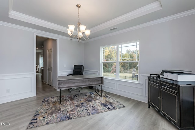 home office with an inviting chandelier, light hardwood / wood-style floors, ornamental molding, and a raised ceiling