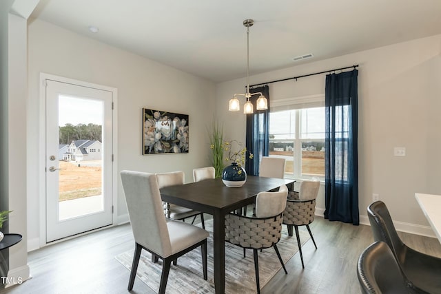 dining space with light hardwood / wood-style floors and a notable chandelier