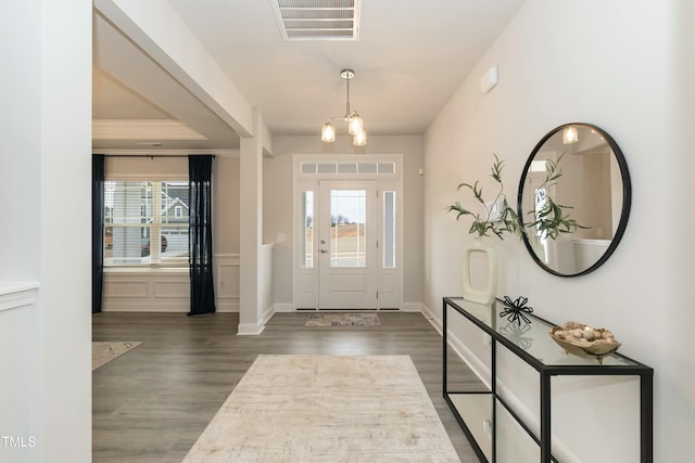 entryway featuring a notable chandelier, ornamental molding, and dark hardwood / wood-style floors