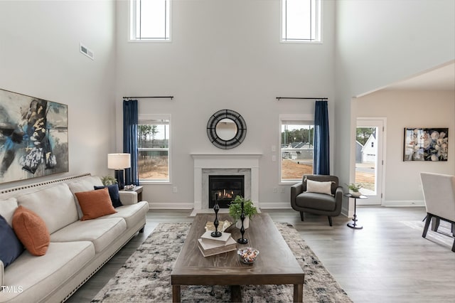 living room with a towering ceiling, light hardwood / wood-style flooring, and a premium fireplace