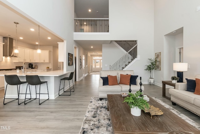 living room with a towering ceiling, sink, and light hardwood / wood-style flooring