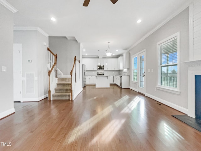 unfurnished living room featuring hardwood / wood-style flooring, crown molding, and ceiling fan