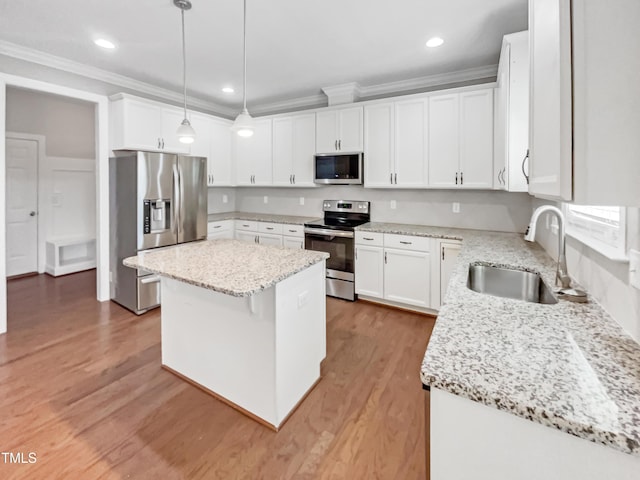 kitchen with appliances with stainless steel finishes, white cabinetry, sink, hanging light fixtures, and a center island