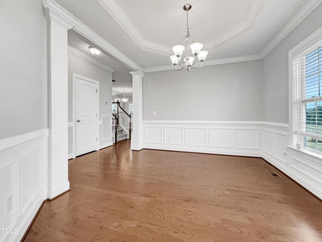 unfurnished dining area featuring a raised ceiling, crown molding, dark wood-type flooring, and a notable chandelier