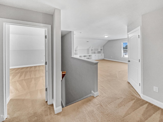 hall featuring lofted ceiling, light carpet, and built in features