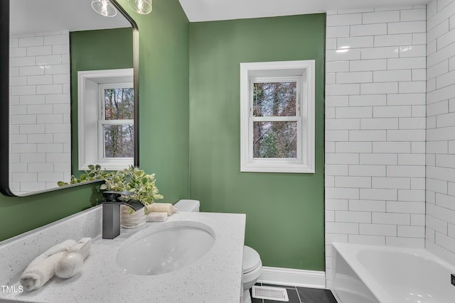 full bathroom featuring tile patterned flooring, vanity, tiled shower / bath combo, and toilet