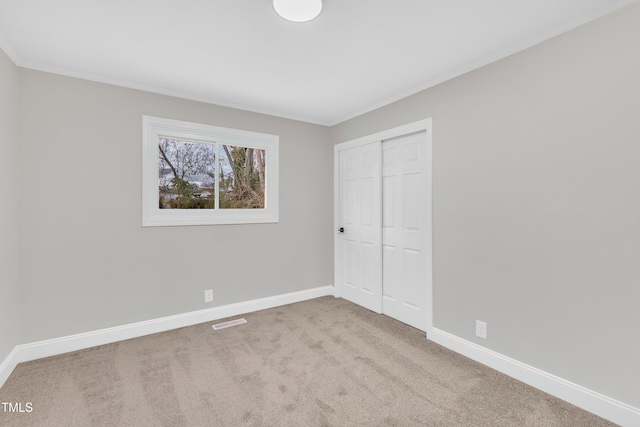 unfurnished bedroom with crown molding, light colored carpet, and a closet