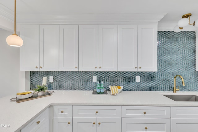 kitchen with tasteful backsplash, white cabinetry, sink, and ornamental molding