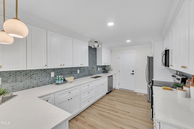 kitchen with sink, hanging light fixtures, stainless steel appliances, white cabinets, and decorative backsplash