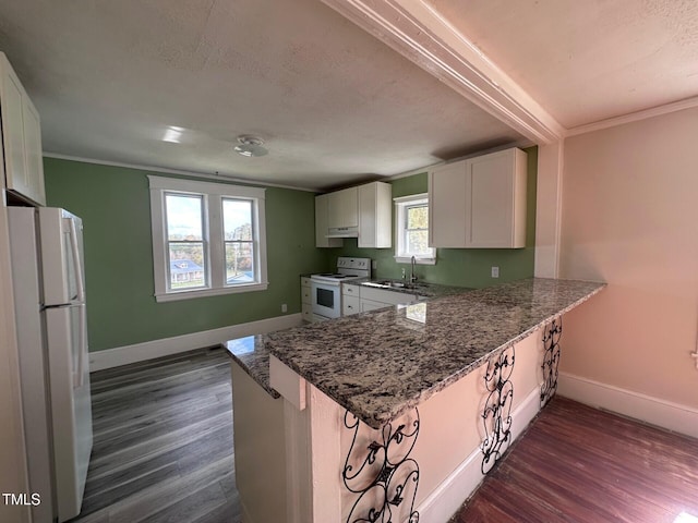 kitchen with white cabinetry, white appliances, kitchen peninsula, and dark stone counters