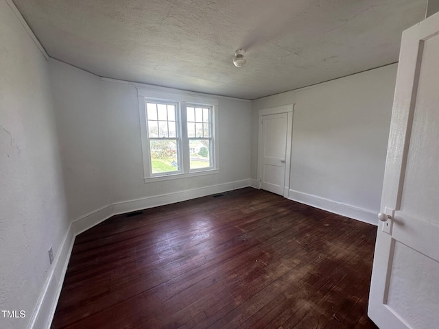 spare room featuring dark hardwood / wood-style floors and a textured ceiling