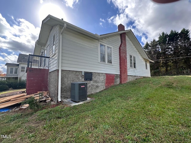 view of home's exterior with cooling unit and a lawn