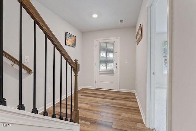 entrance foyer with wood finished floors, baseboards, stairway, and visible vents