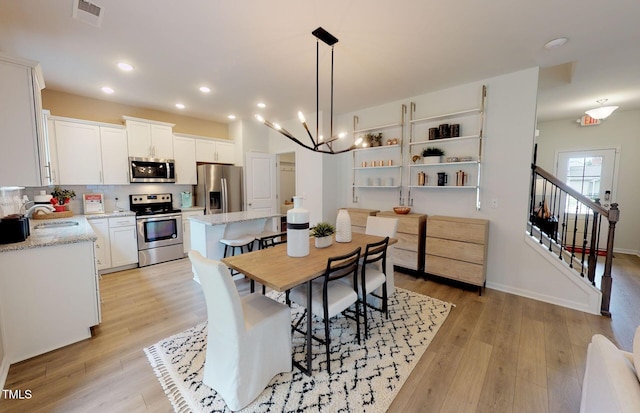 dining space featuring sink, light hardwood / wood-style flooring, and a chandelier