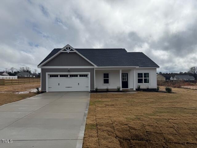 craftsman-style house featuring a garage, driveway, fence, and a front yard