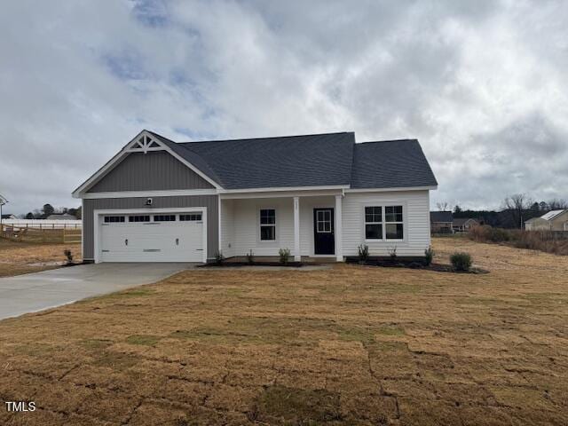 view of front of home featuring a garage, concrete driveway, roof with shingles, and a front lawn