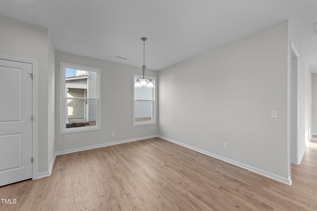 unfurnished dining area featuring a chandelier and light wood-type flooring