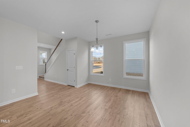 unfurnished dining area with an inviting chandelier, light hardwood / wood-style flooring, and plenty of natural light