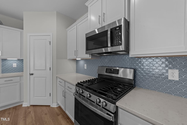 kitchen with backsplash, white cabinets, and appliances with stainless steel finishes