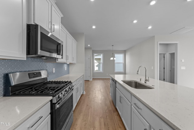 kitchen with white cabinetry, sink, light stone counters, and appliances with stainless steel finishes