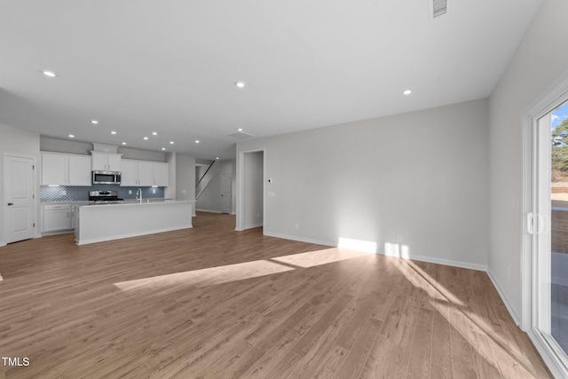 unfurnished living room with sink and light hardwood / wood-style floors