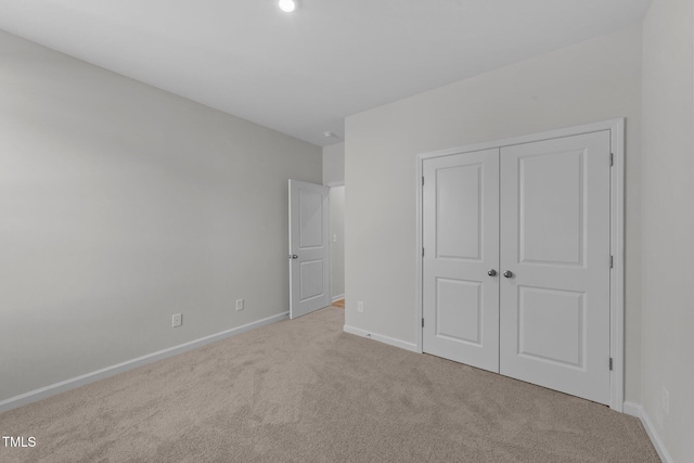 unfurnished bedroom featuring light colored carpet and a closet