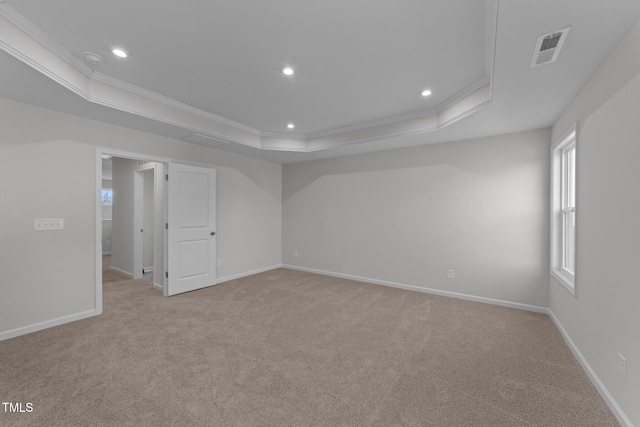 carpeted spare room featuring ornamental molding and a raised ceiling