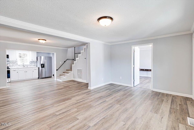 spare room with crown molding, light hardwood / wood-style flooring, and a textured ceiling