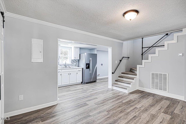 interior space featuring sink, a textured ceiling, ornamental molding, hardwood / wood-style flooring, and a barn door