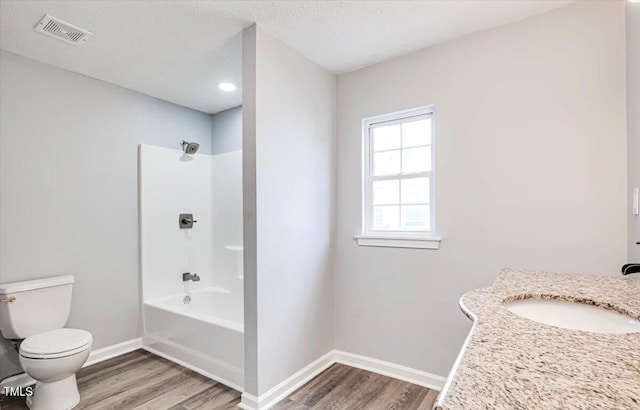 full bathroom featuring hardwood / wood-style floors, a textured ceiling, tub / shower combination, and toilet