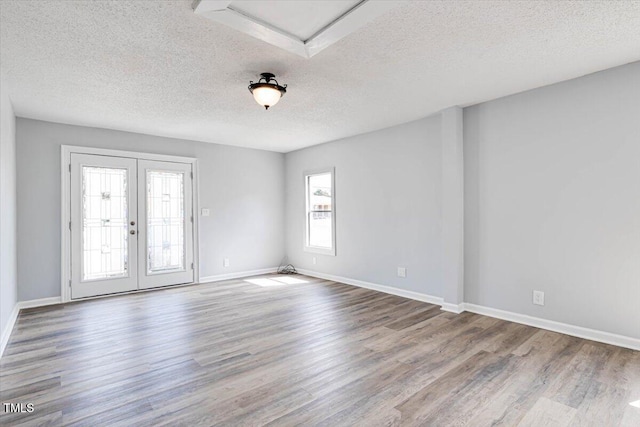 spare room with wood-type flooring, french doors, and a textured ceiling