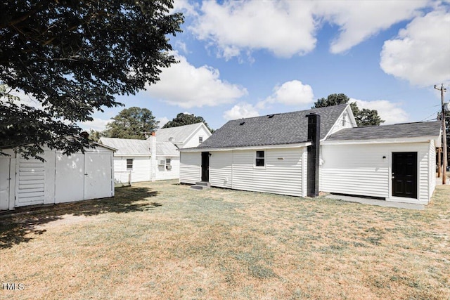 rear view of property featuring a lawn and a storage unit