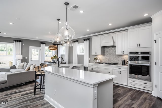 kitchen featuring premium range hood, appliances with stainless steel finishes, white cabinets, and a spacious island