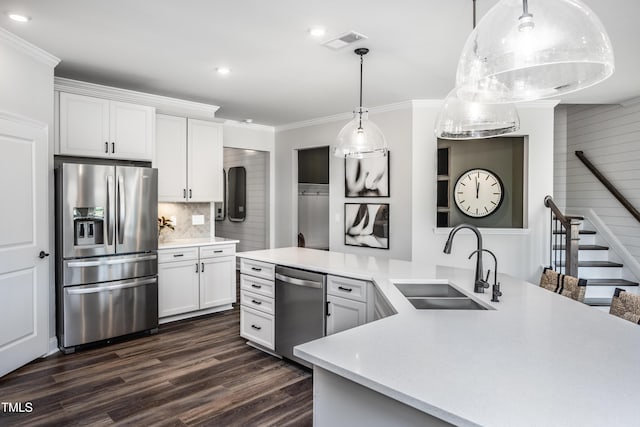 kitchen featuring pendant lighting, sink, crown molding, appliances with stainless steel finishes, and white cabinetry