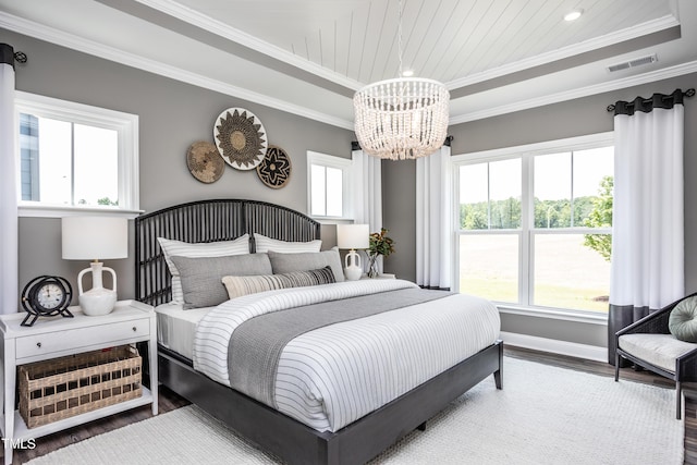 bedroom with wood-type flooring, a raised ceiling, multiple windows, and a notable chandelier