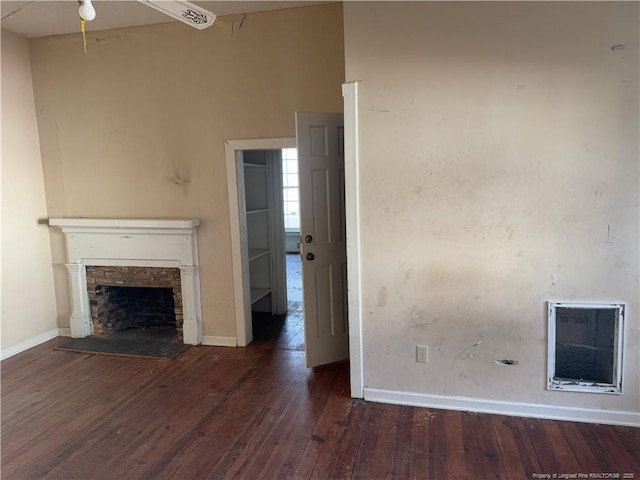 unfurnished living room featuring dark wood-type flooring and a stone fireplace