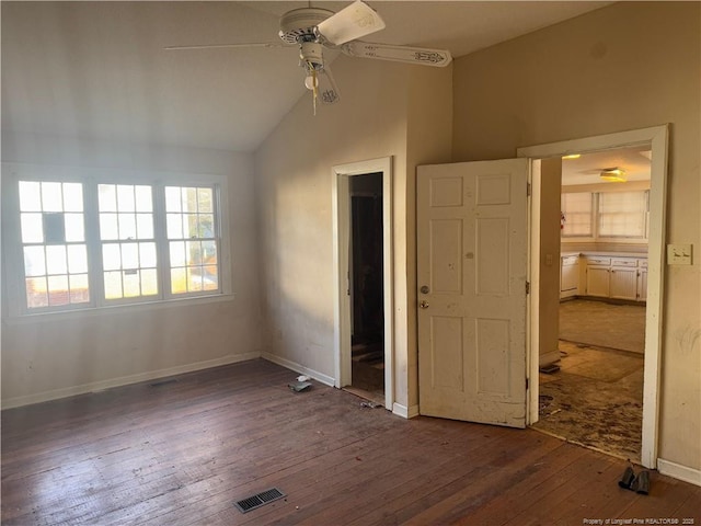 unfurnished bedroom featuring ensuite bathroom, vaulted ceiling, dark hardwood / wood-style floors, and ceiling fan